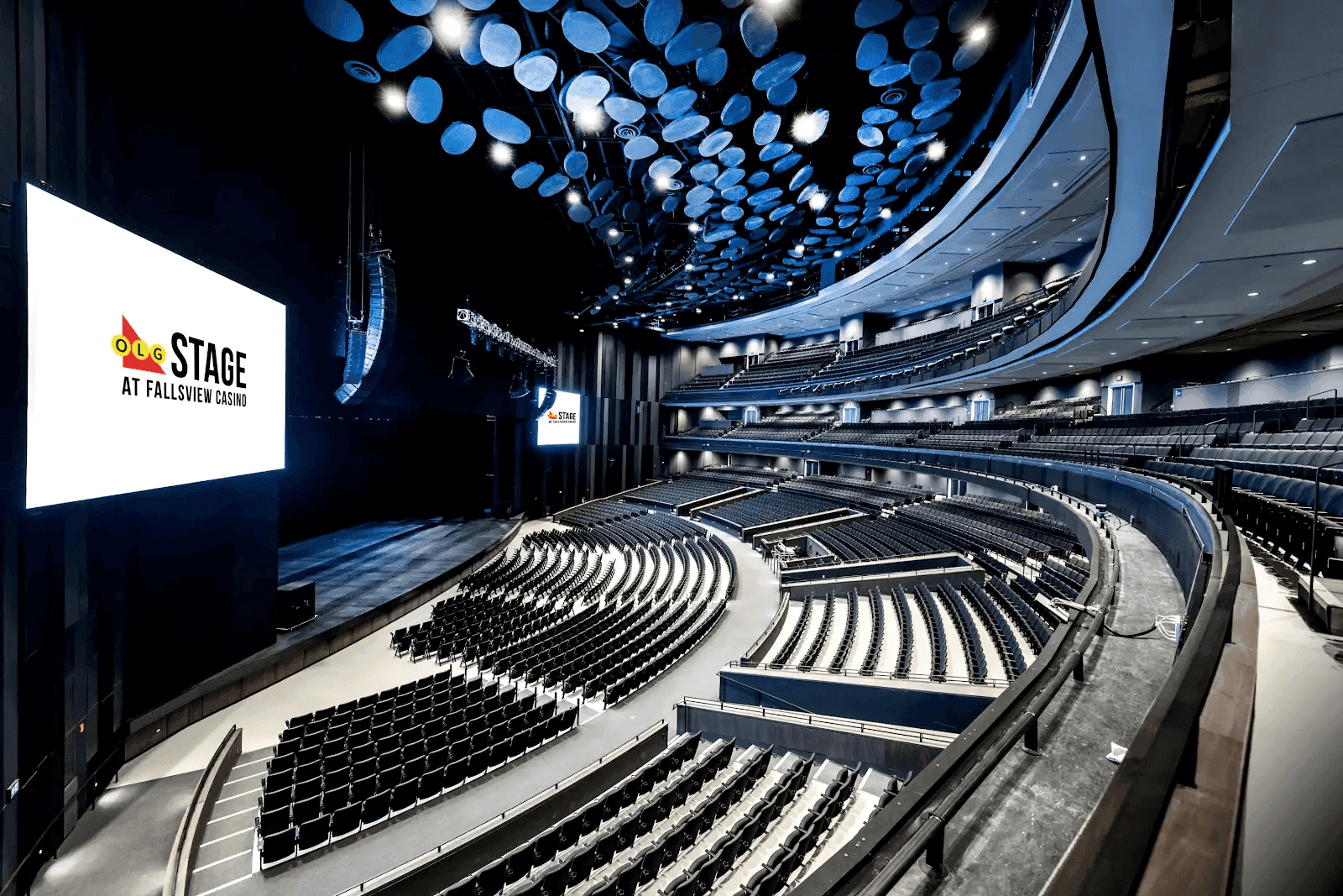 An expansive theater with modern finishes, two screens and a large stage.